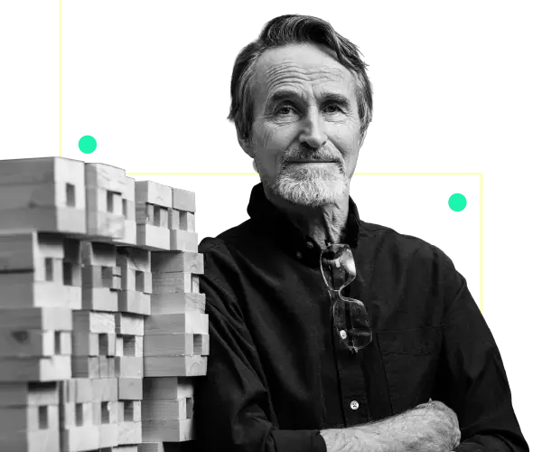 man in him 60s standing next to a pile of wood